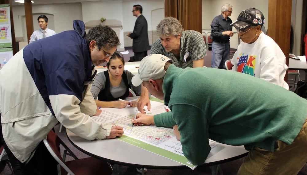 A group of people reviewing a large print-out of a graph