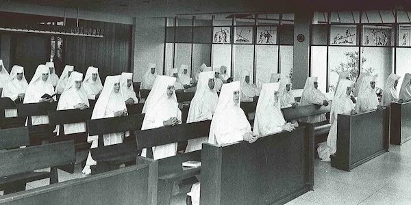 The Franciscan Sisters of Allegany inside of a church during Sunday mass kneeling as they pray