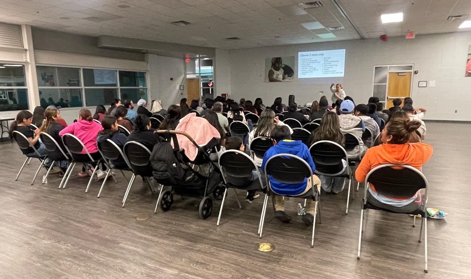 A group of people in chairs watching a powerpoint presentation