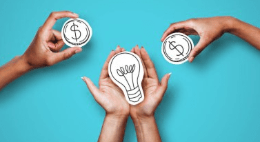 A pair of hands holding a paper cutout lightbulb while two other hands hold paper cutout coins